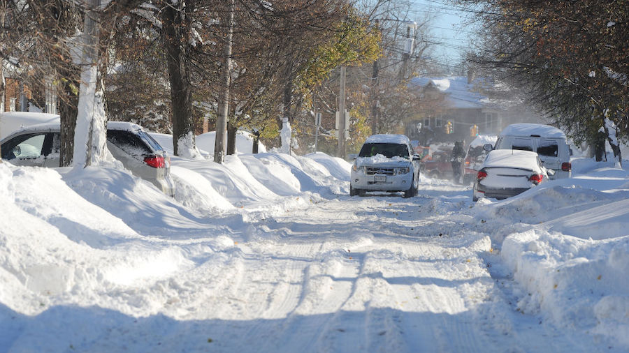 Cars make their way through tree lined streets  after an intense lake-effect snowstorm that impacte...