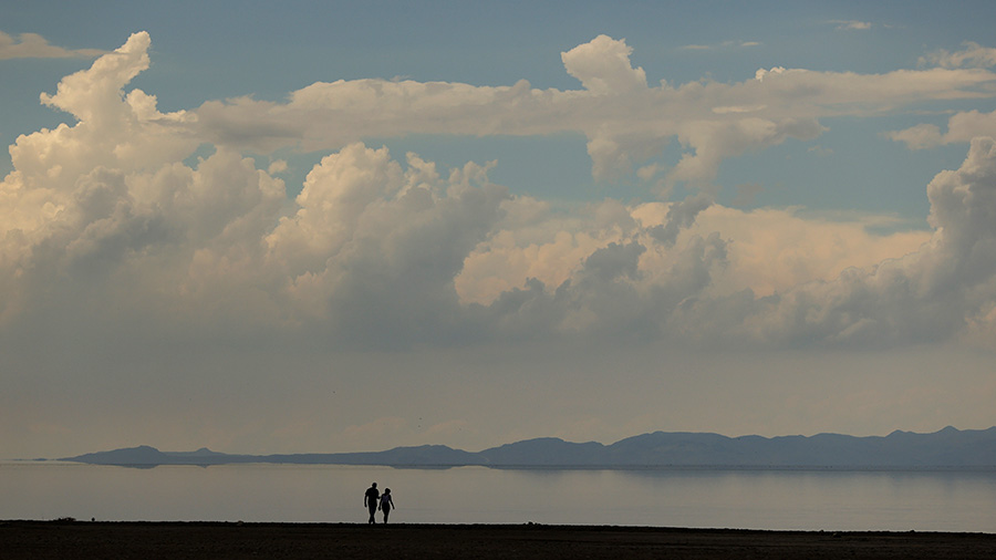 Two walking near Great Salt Lake, with dusty air in horizon...
