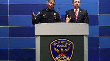 A police officer making an announcement behind a podium for the San Francisco Police Department