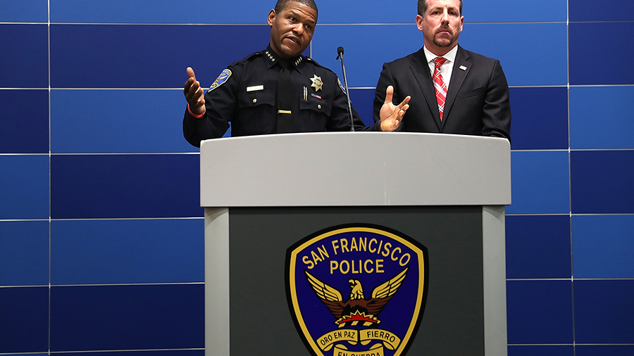 A police officer making an announcement behind a podium for the San Francisco Police Department...