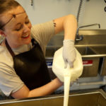 Mountain Born Creamery’s Baylee Sorenson pour a gallon of cream into a butter churn as she makes artisan butter. (KSL TV)
