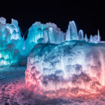 Ice Castles lit in pink and blue shades like cotton candy. (Ice Castles)