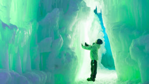 A kid is looking up at tall ice surrounding him.
