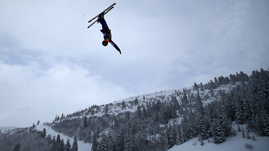 A skier is in the air with a mountain ski resort in the background...