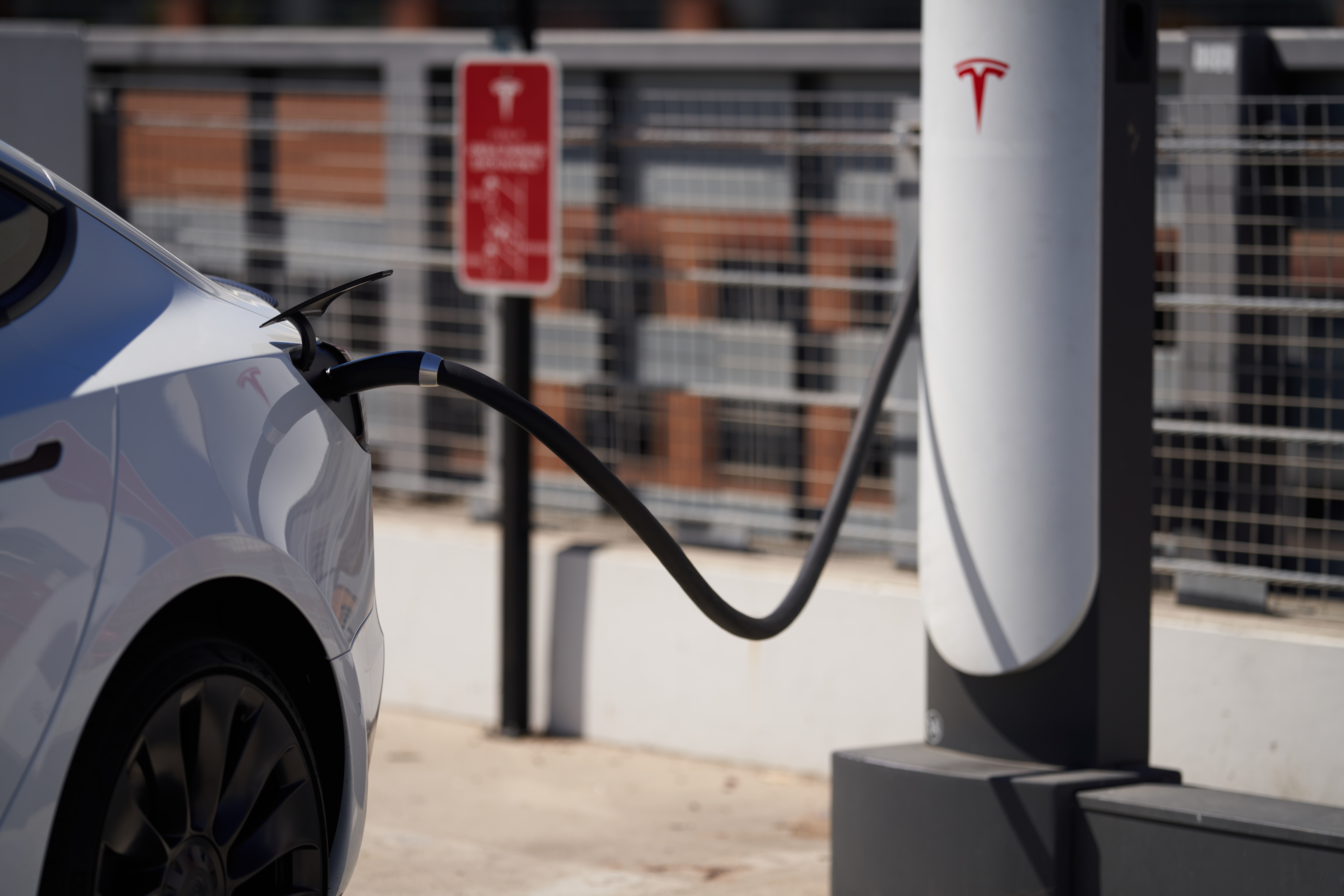 A Tesla vehicle is plugged into a Tesla charging station in a parking lot on September 22, 2022 in ...