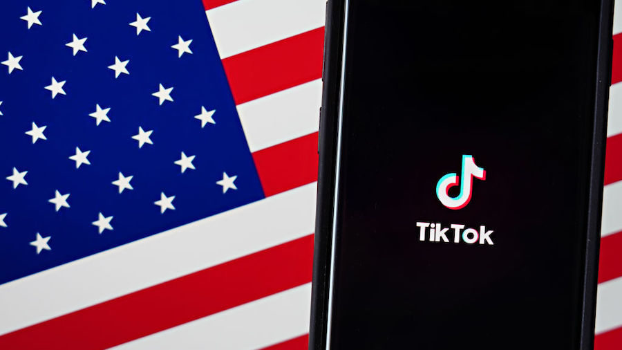 FILE: In this photo illustration, a mobile phone featuring the TikTok app is displayed next to the ...