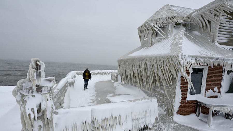 A man near a house completely covered in ice after snowfall in Buffalo, New York, on December 26. (...