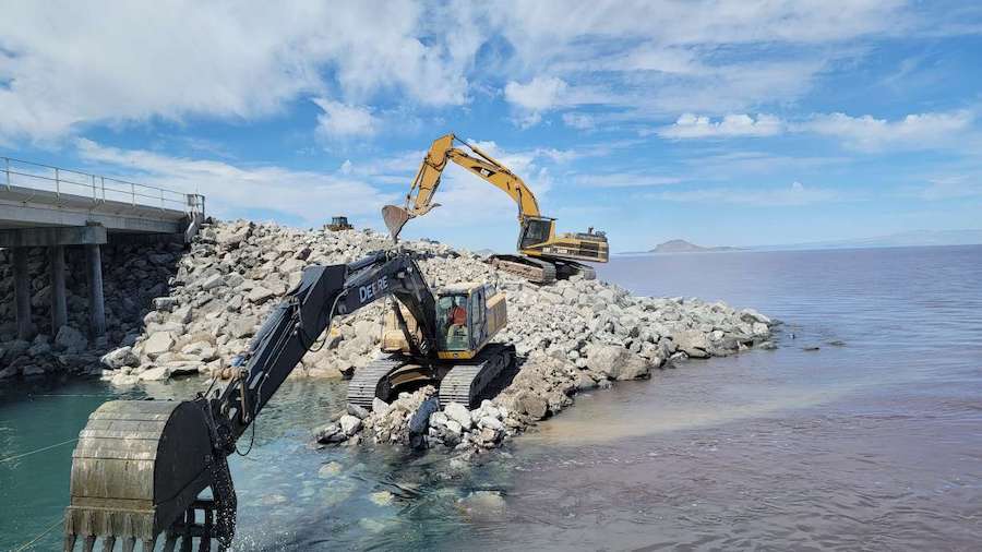 Crews use an excavator to move stones at the Great Salt Lake Causeway to raise the berm by 4 feet i...
