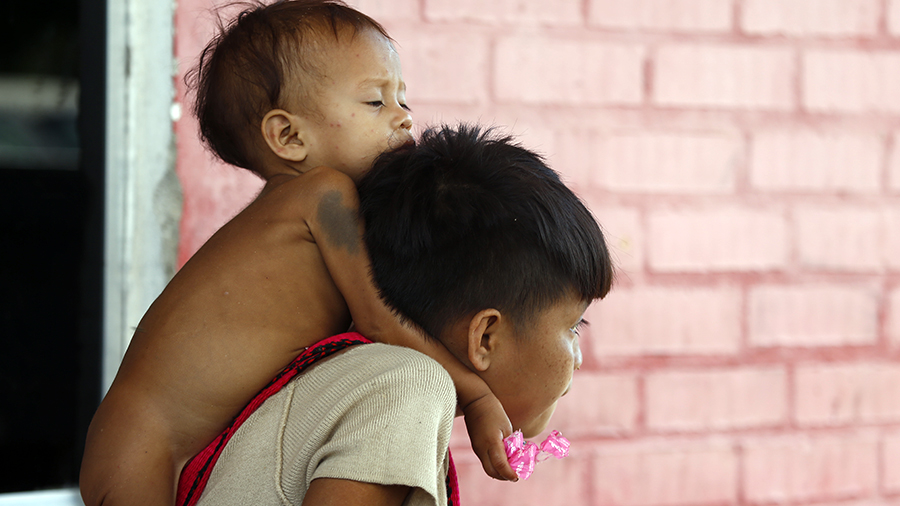 A Yanomami youth carries a toddler on his shoulders at the Saude Indigenous House, a center respons...