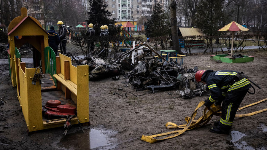 Firemen roll up hoses in front of debris as emergency service workers respond at the site of a heli...