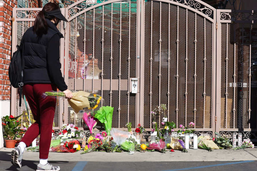 A person walks to place flowers at a makeshift memorial outside the scene of a deadly mass shooting...