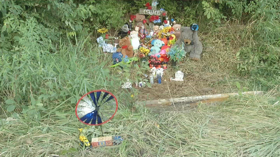 grave memorial with toys and flowers near ditch...