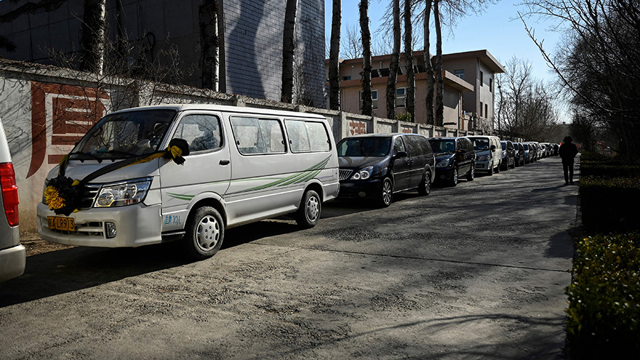 hearses lined up on the side of a city road in China...