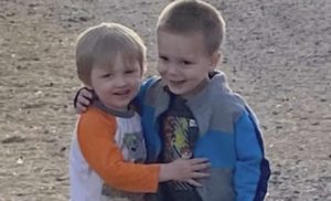 Two boys hugging and smiling.
