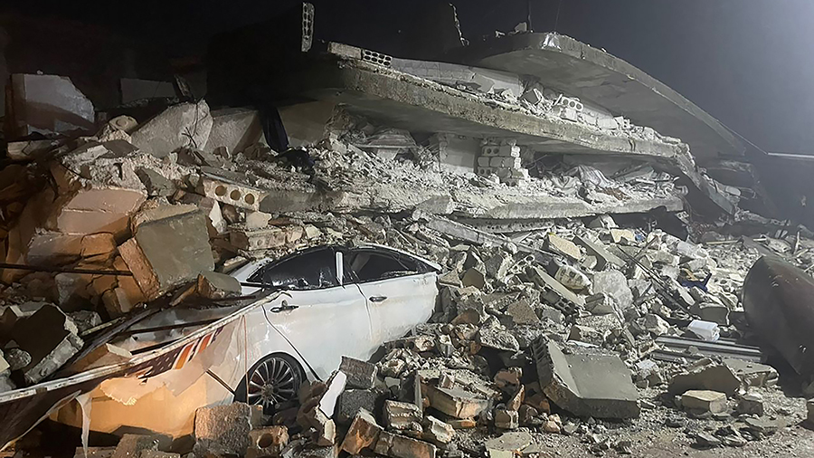 A car is seen under the wreckage of a collapsed building, in Azmarin town, in Idlib province, north...