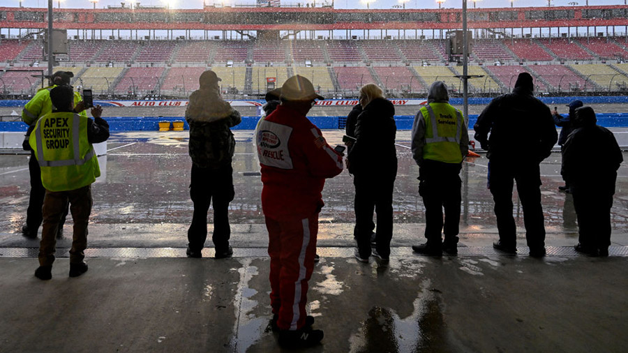 FONTANA, CALIFORNIA - FEBRUARY 25: Track staff look on as snowfalls at the track after a weather ca...