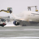 Crews cleaning off ice on an airplane. (KSLTV/Mark Less)