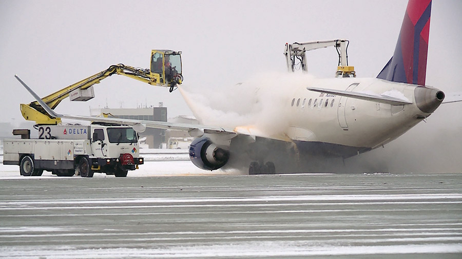 Crews cleaning off ice on an airplane. (KSLTV/Mark Less)...