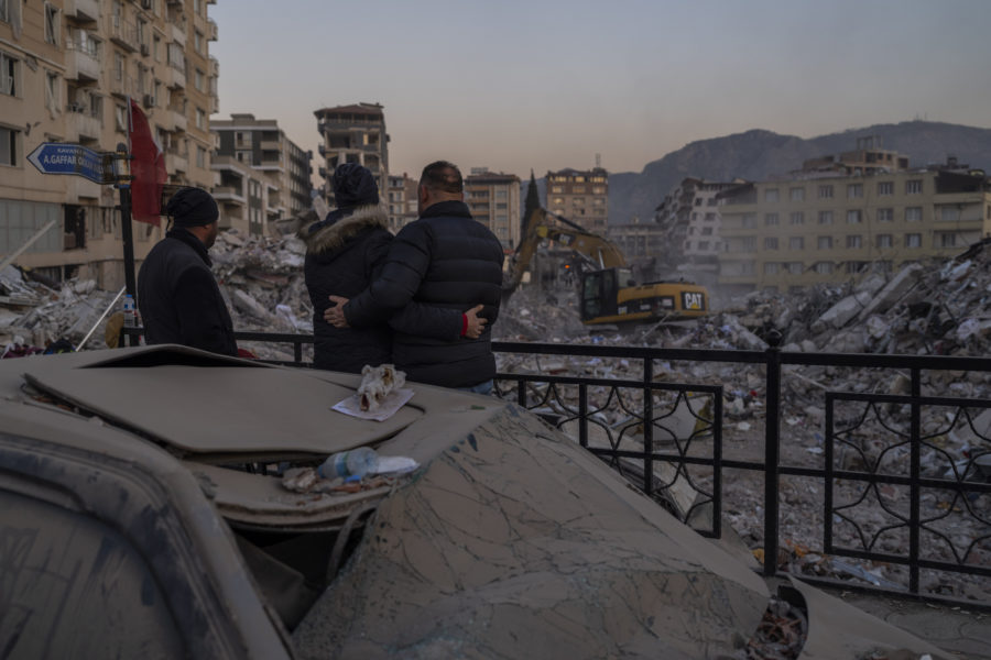 Men observe the site of collapsed buildings during the earthquake in Antakya, southeastern Turkey, ...