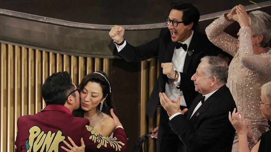 Daniel Kwan embraces Michelle Yeoh after he and Daniel Scheinert won the Oscar for best original sc...