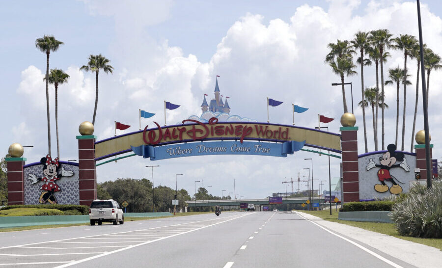 FILE - Cars drive under a sign greeting visitors near the entrance to Walt Disney World, July 2, 20...