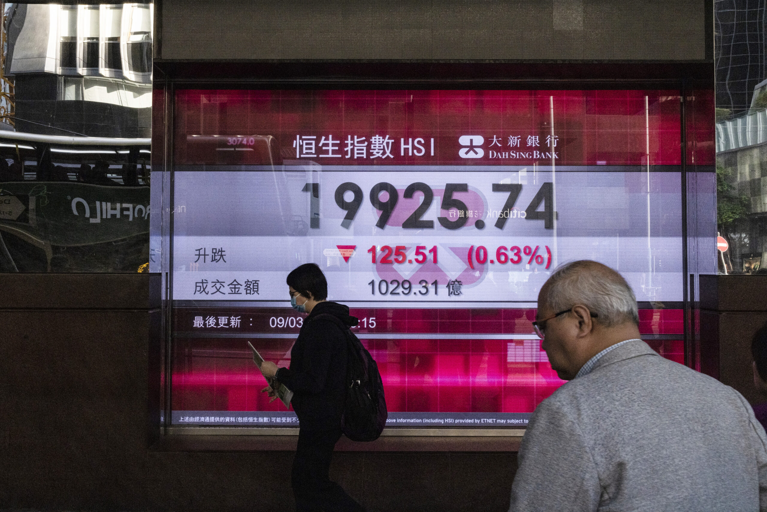 People walk by the Dah Sing Bank's electronic screen in Hong Kong on Friday, March 10, 2023. Asian ...