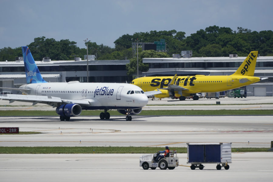 FILE - A JetBlue Airways Airbus A320, left, passes a Spirit Airlines Airbus A320 as it taxis on the...