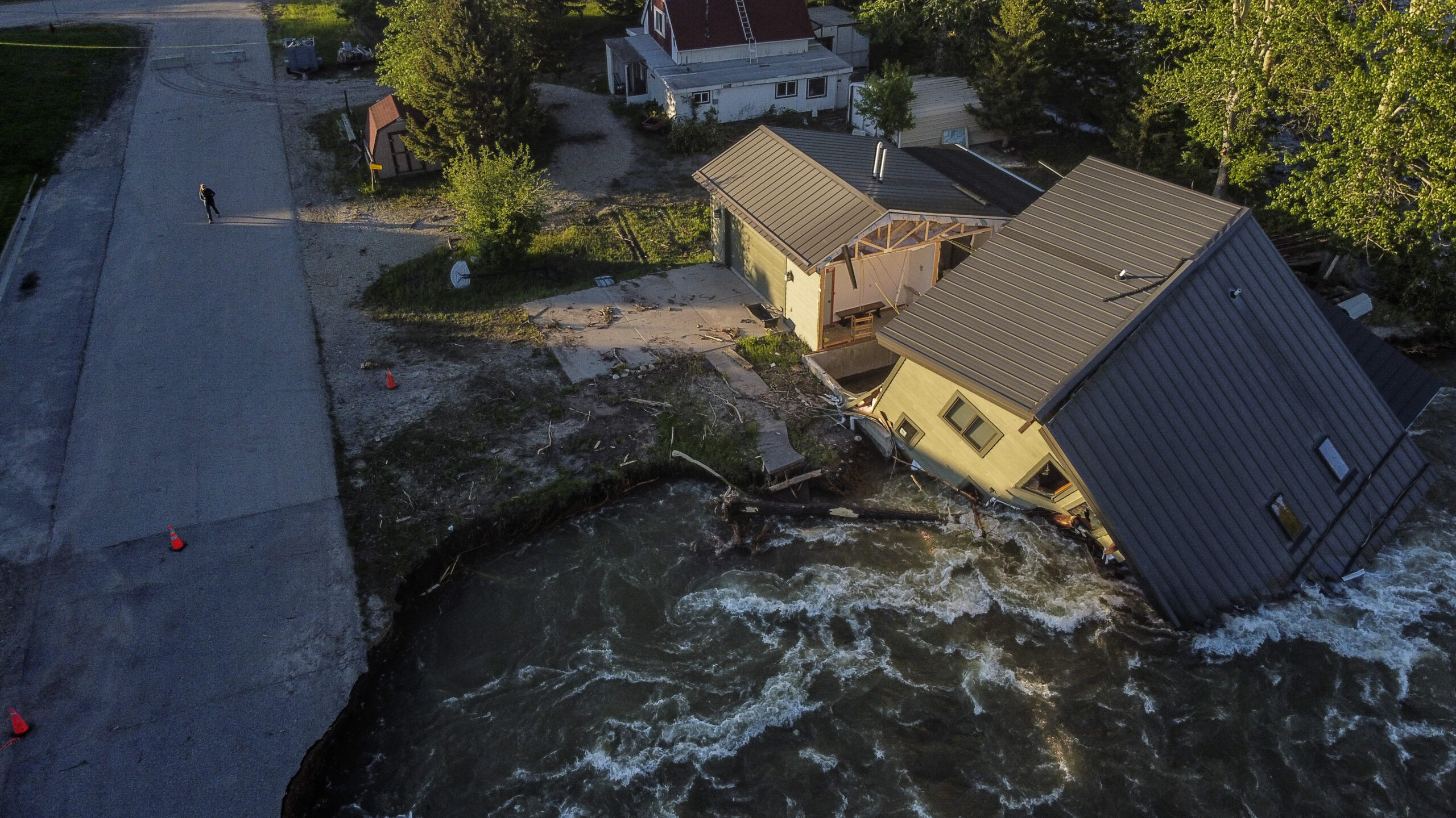 FILE - A house sits in Rock Creek after floodwaters washed away a road and a bridge in Red Lodge, M...