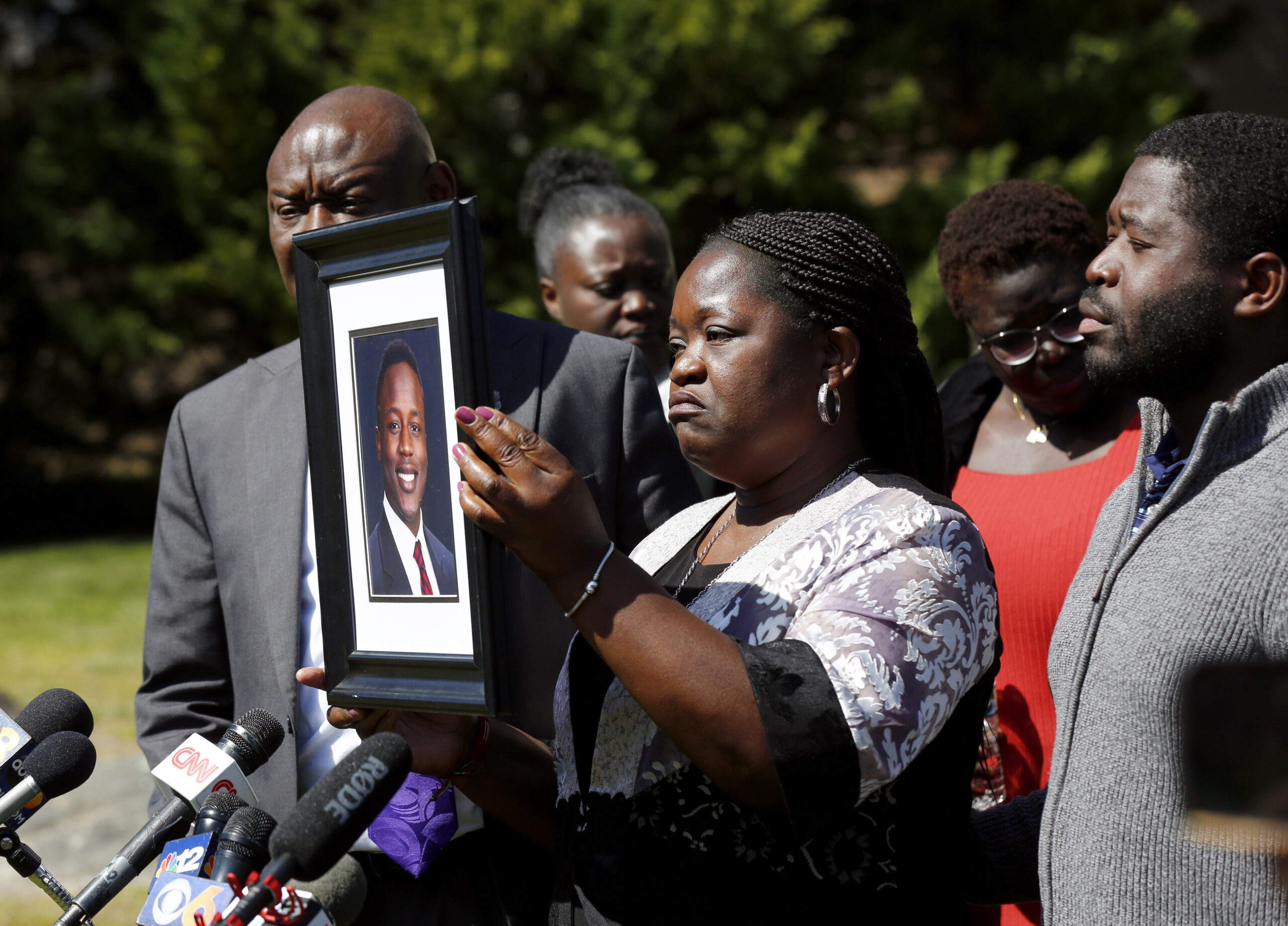 Caroline Ouko, mother of Irvo Otieno, holds a portrait of her son with attorney Ben Crump, left, an...
