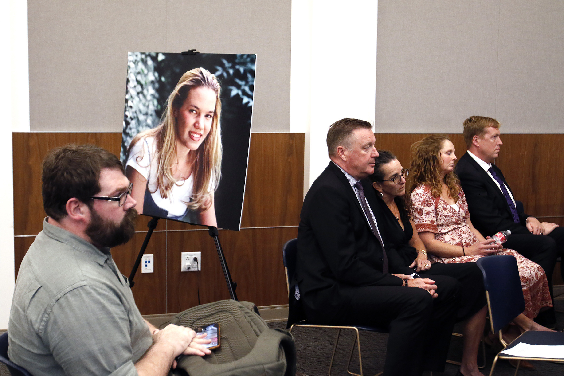 FILE - Chris Lambert, documentary podcaster, sits in front of a poster of Kristin Smart with family...