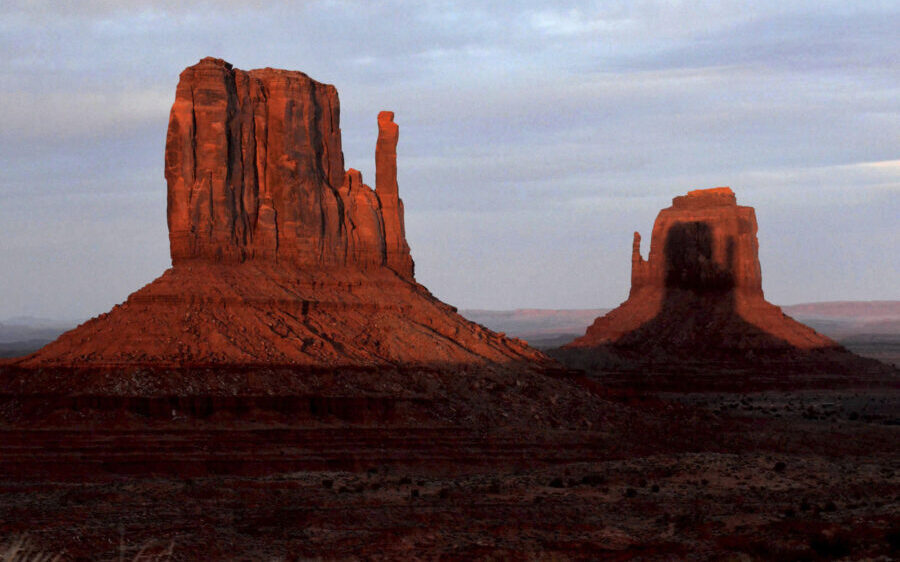 A sunset spectacle featuring two mitten-shaped rock formations crosses Monument Valley Tribal Park ...