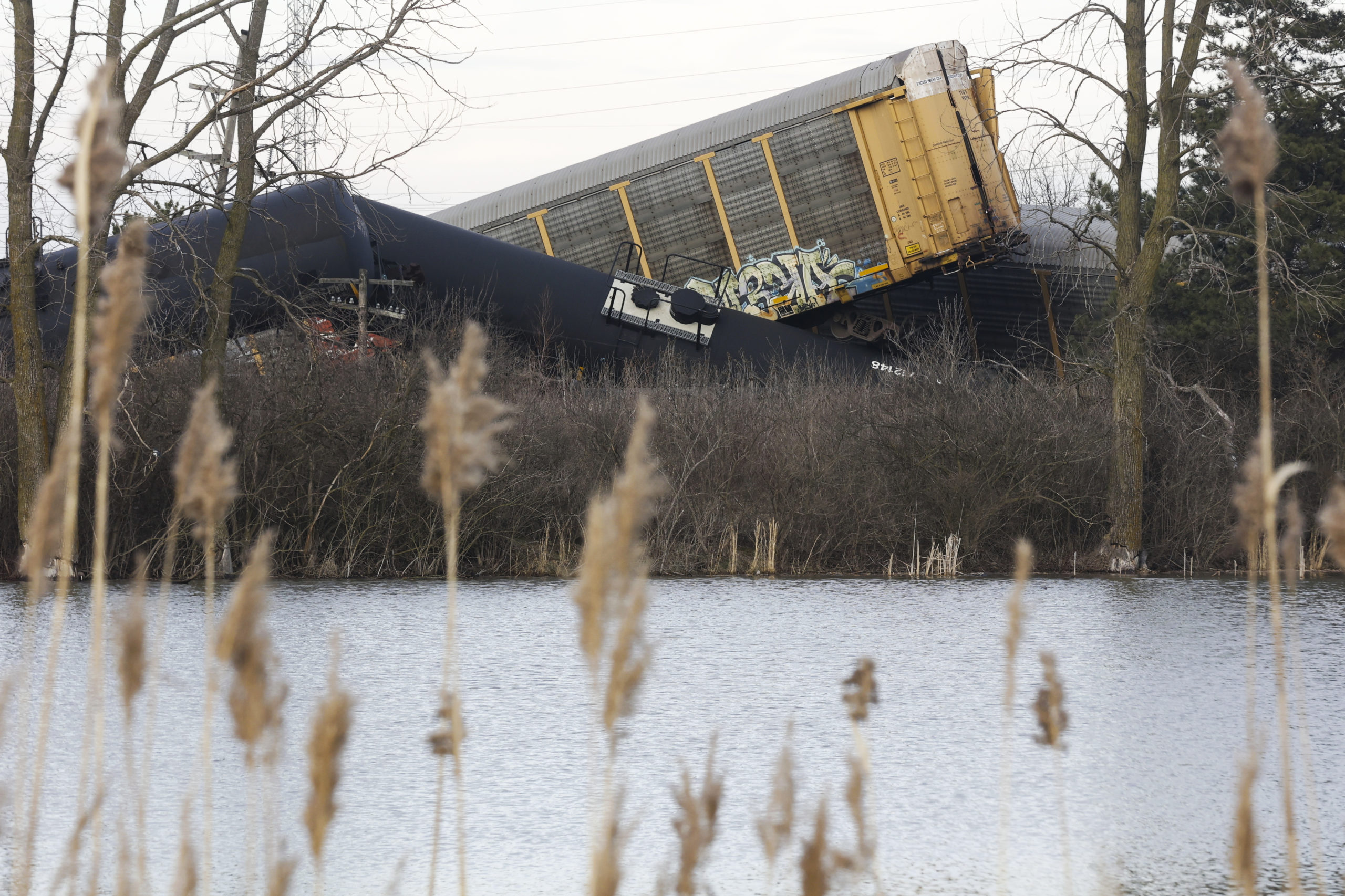 Multiple cars of a Norfolk Southern cargo train lie toppled on one another after derailing at a tra...
