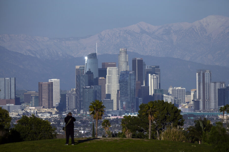 A visitor takes in a view of the city's skyline under the snow-covered San Gabriel mountains after ...