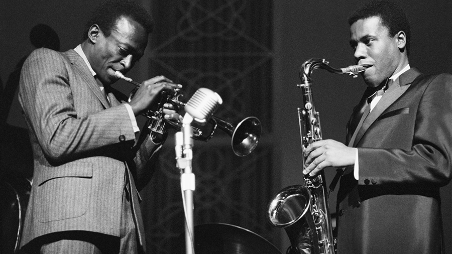 Miles Davis playing trumpet and Wayne Sorter playing saxophone on stage....