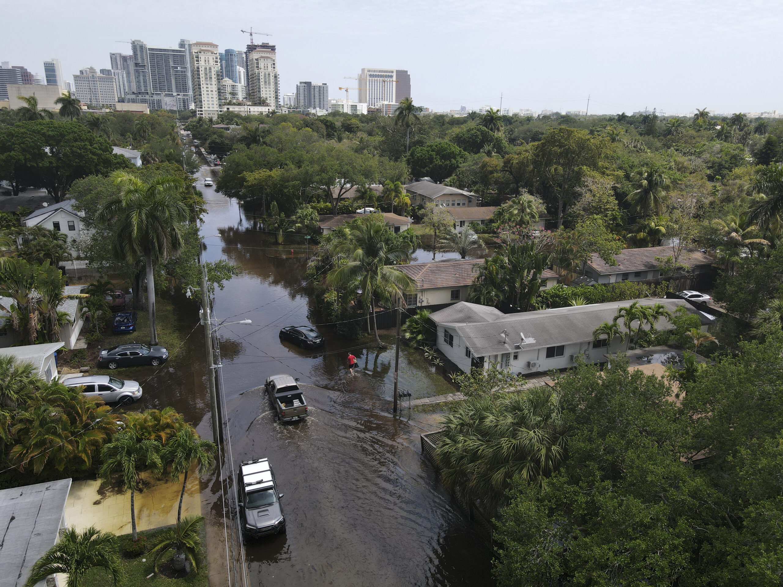 In this photo taken with a drone, trucks and a resident on foot make their way through receding flo...