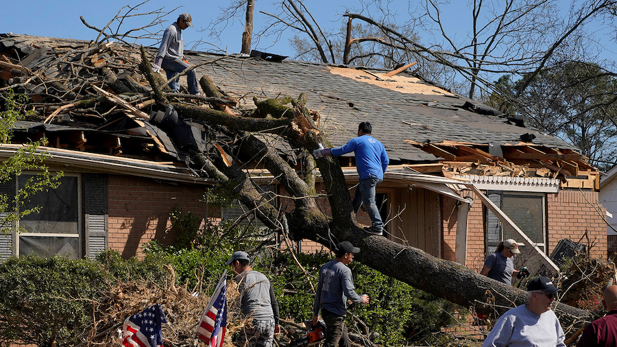 People work to remove a tree that fell onto a home, in the aftermath of a tornado in Little Rock, A...