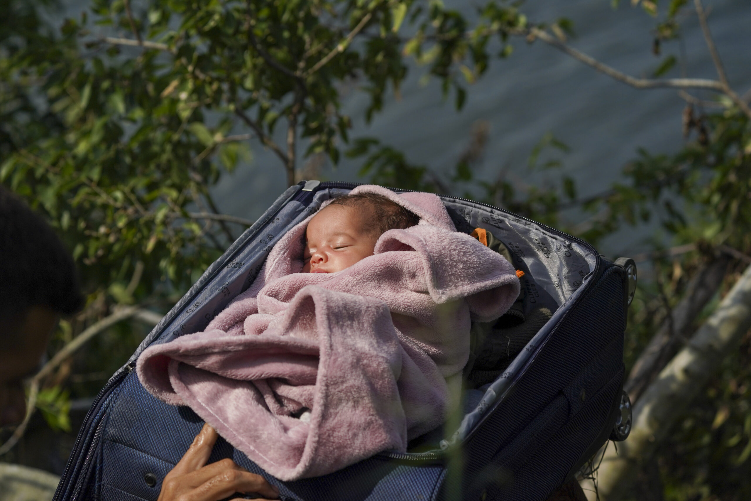 Migrants cross the Rio Grande into the U.S. with a baby in a suitcase, as seen from Matamoros, Mexi...