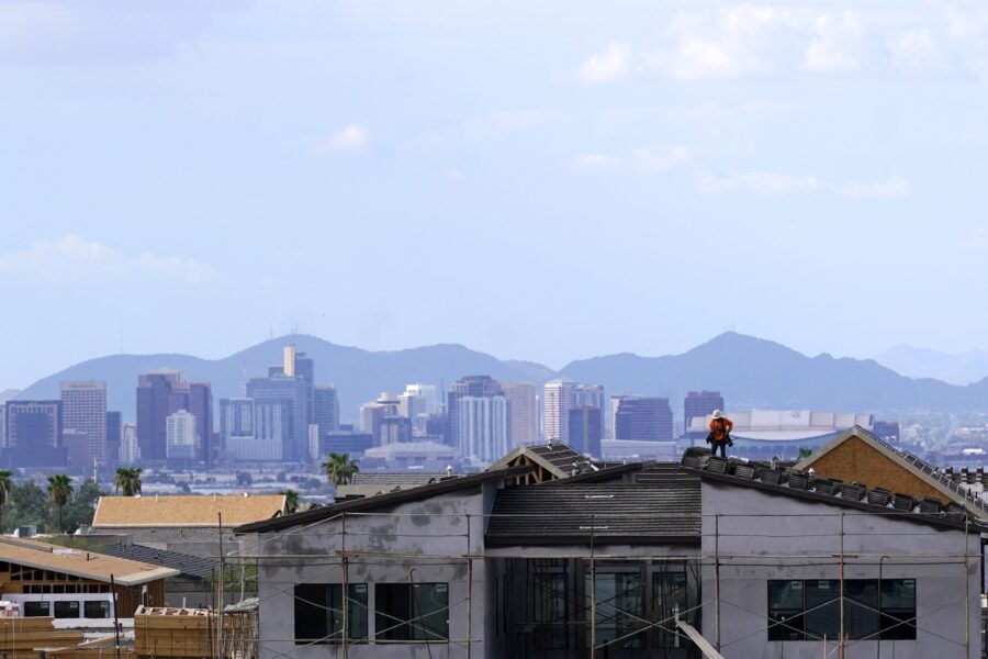 FILE - In this Aug. 12, 2021, file photo with the downtown skyline in the background, a roofer work...