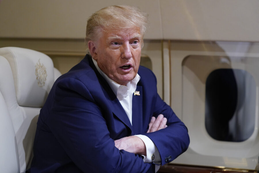 FILE - Former President Donald Trump speaks with reporters while in flight on his plane after a cam...