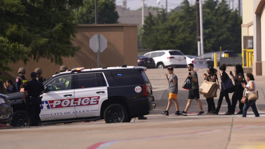 People raise their hands as they leave a shopping center following reports of a shooting, Saturday,...