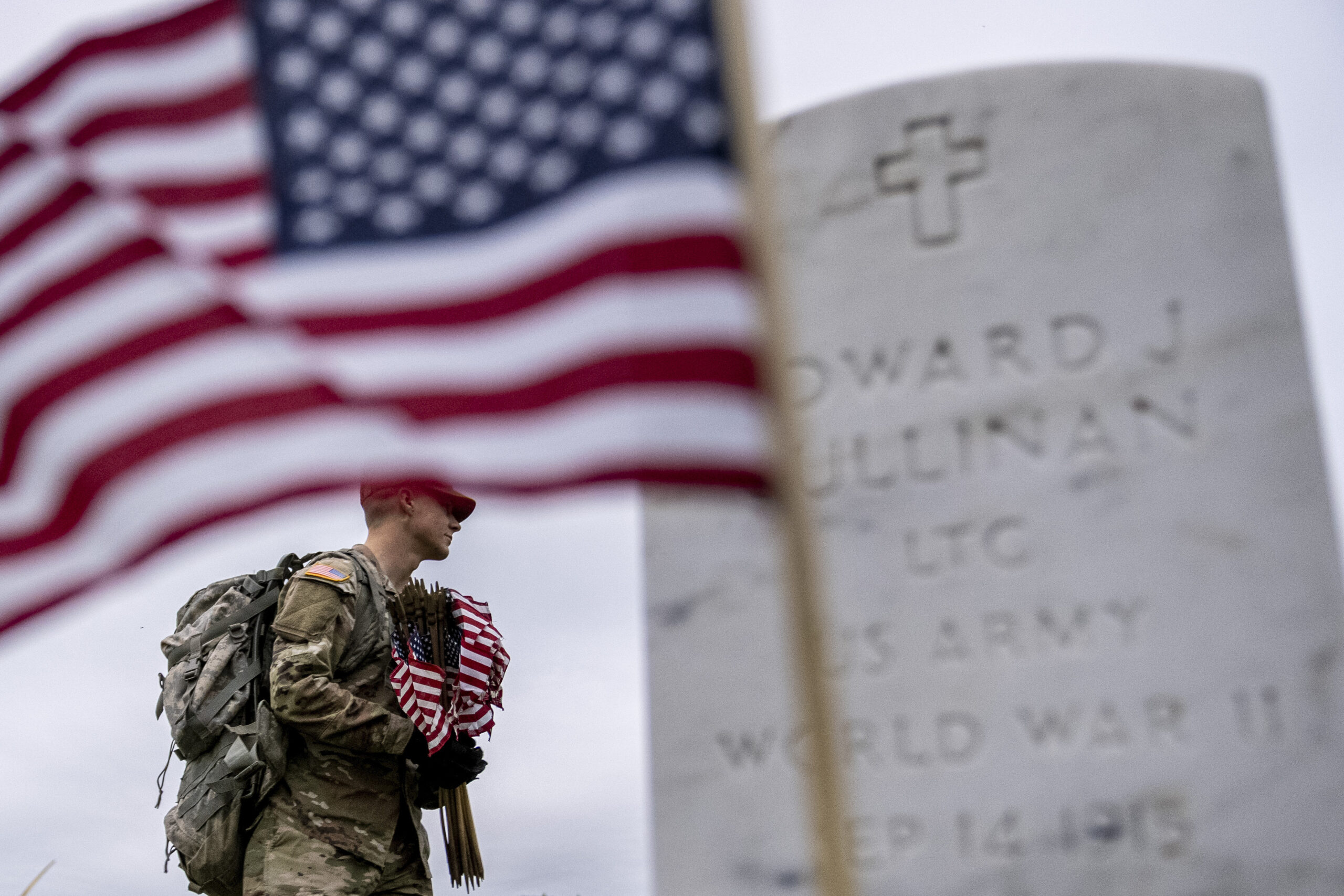 A member of the 3rd U.S. Infantry Regiment, also known as The Old Guard, places flags in front of e...