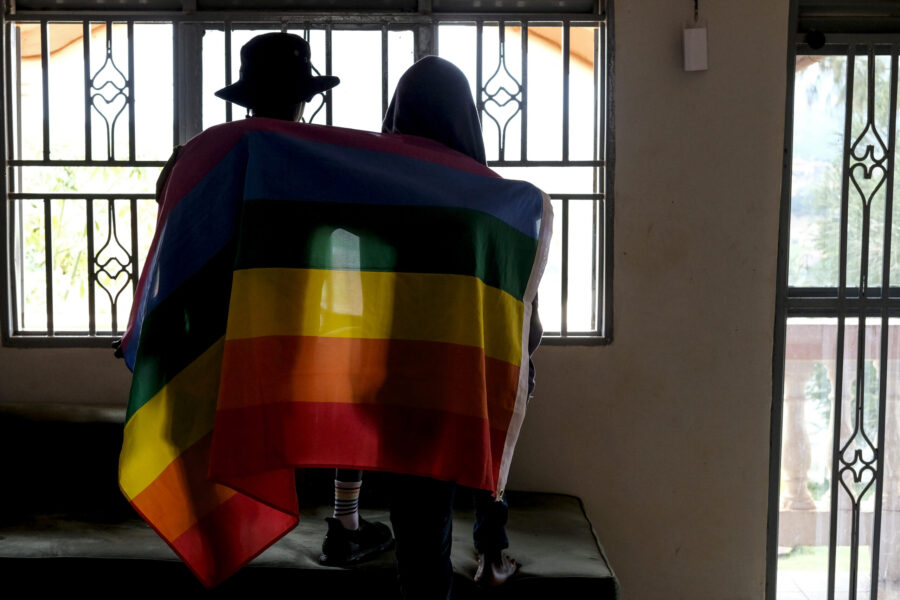 FILE - A gay Ugandan couple cover themselves with a pride flag as they pose for a photograph in Uga...