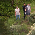 Three men discuss the car that went into the water at Settlement Canyon Reservoir in Tooele County where a 12-year-old girl had to be pulled from the submerged car and revived with CPR. (Greg Anderson/KSL TV)