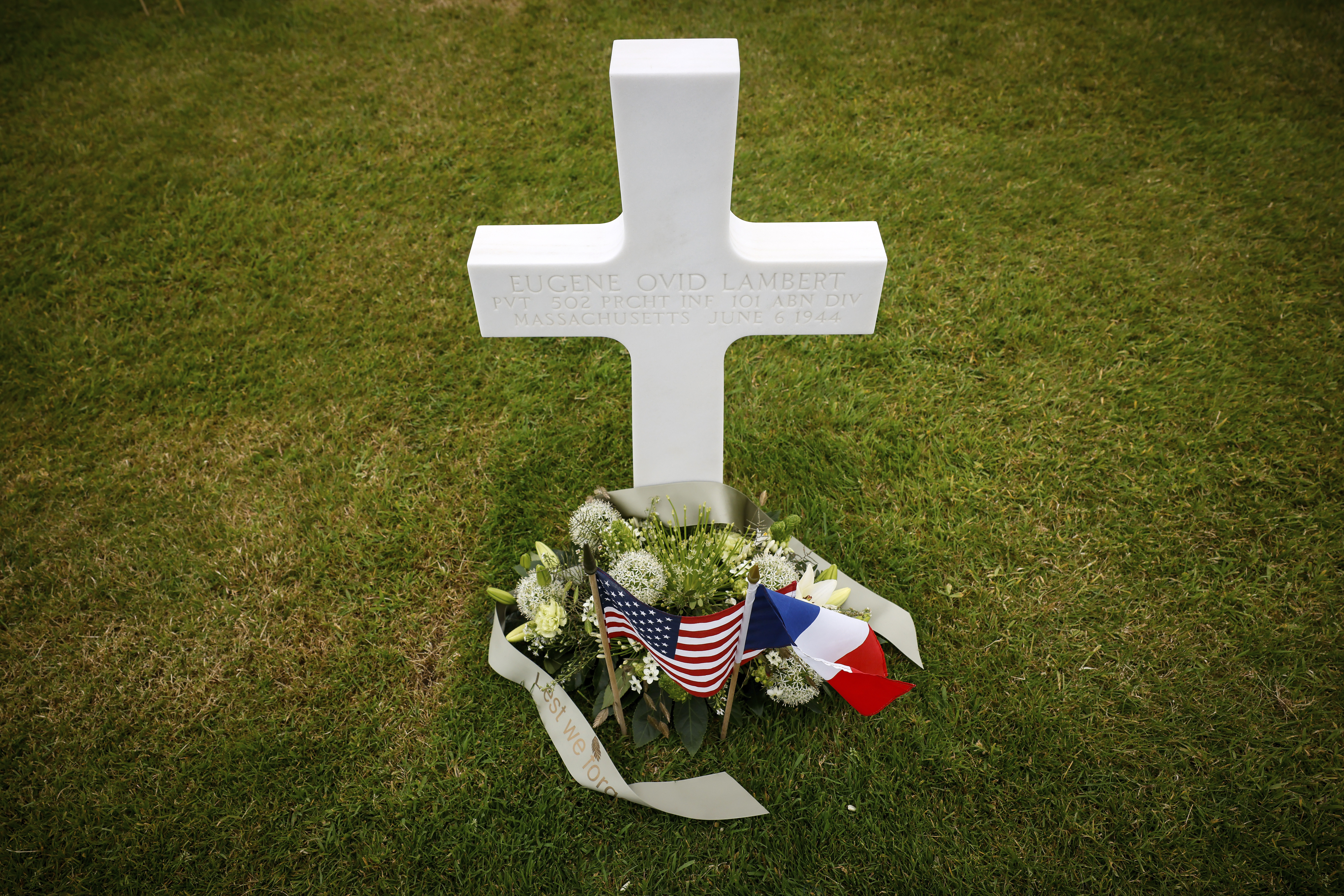 An American flag, left, and French flag lay at headstones in the American Cemetery in Colleville-su...