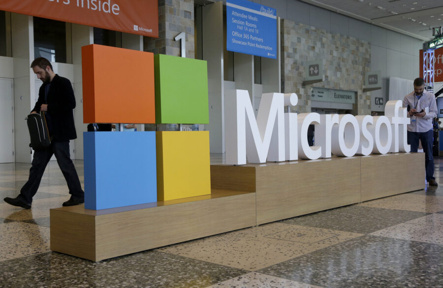 FILE - A man walks past a Microsoft sign set up for the Microsoft BUILD conference, April 28, 2015,...