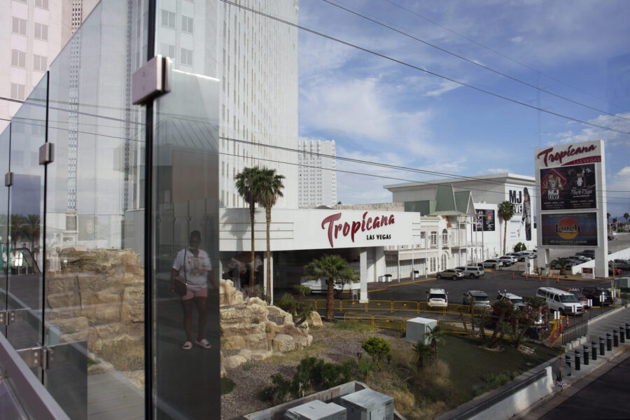FILE - A person, reflected in glass, walks near the Tropicana Las Vegas on May 16, 2023, in Las Veg...