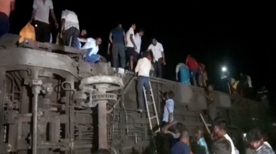 People try to escape from toppled compartments, following the deadly collision of two trains, in Ba...