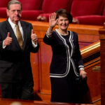 Patricia T. Holland greets the audience while her husband, Elder Jeffrey R. Holland, gives two thumbs up at the October 2012 General Conference. (Church of Jesus Christ of Latter-day Saints)