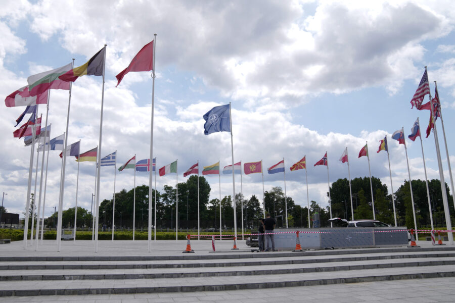 FILE - Two men do construction work around the flags at NATO headquarters in Brussels, Thursday, Ju...
