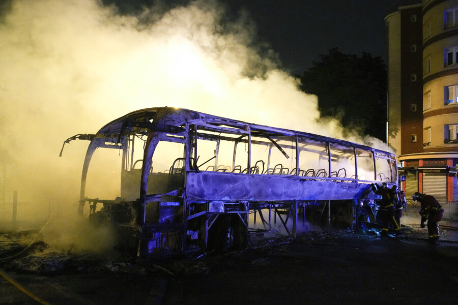 Firefighters use a water hose on a burnt bus in Nanterre, outside Paris, France, Saturday, July 1, ...